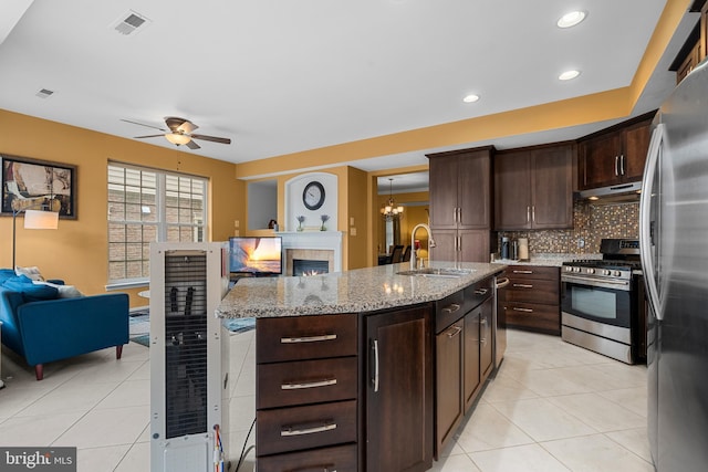 42496 Legacy Park Dr, Brambleton, VA 20148 - kitchen with stainless steel appliances, a sink, open floor plan, under cabinet range hood, and a tile fireplace