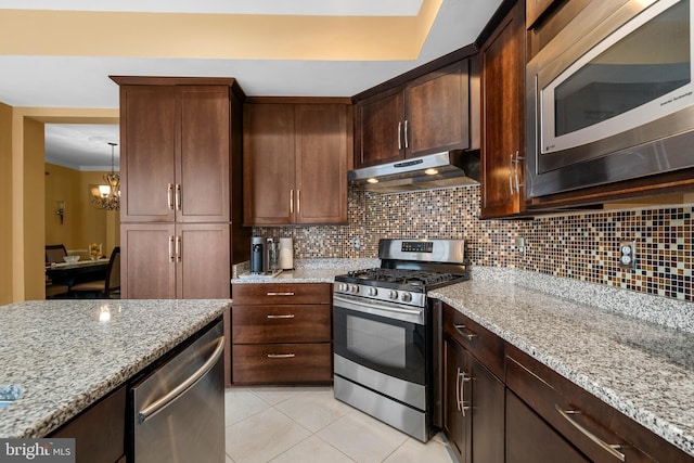 42496 Legacy Park Dr, Brambleton, VA 20148 - kitchen featuring stainless steel appliances, under cabinet range hood, backsplash, light stone counters, and crown molding