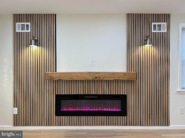 interior details featuring a glass covered fireplace and wood finished floors