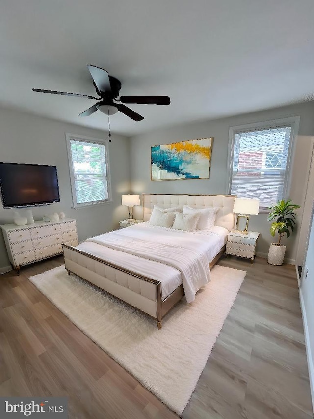 bedroom with wood finished floors, baseboards, and a ceiling fan