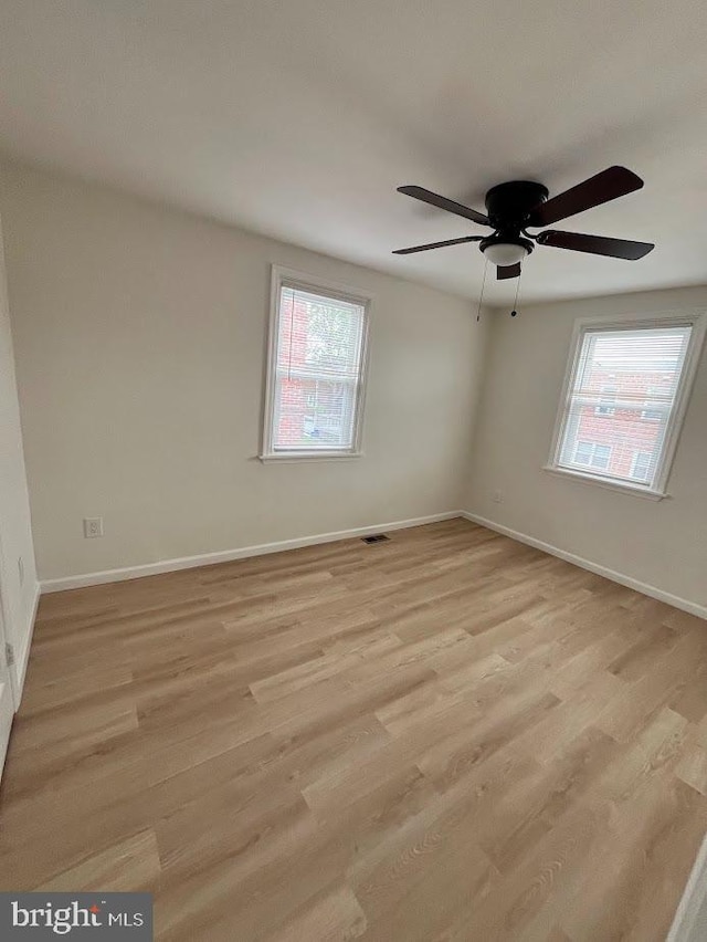 spare room with ceiling fan, light wood-style flooring, baseboards, and plenty of natural light