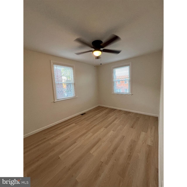 empty room featuring light wood-style flooring, a wealth of natural light, and baseboards