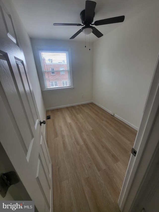 spare room featuring baseboards, light wood-style floors, visible vents, and a ceiling fan