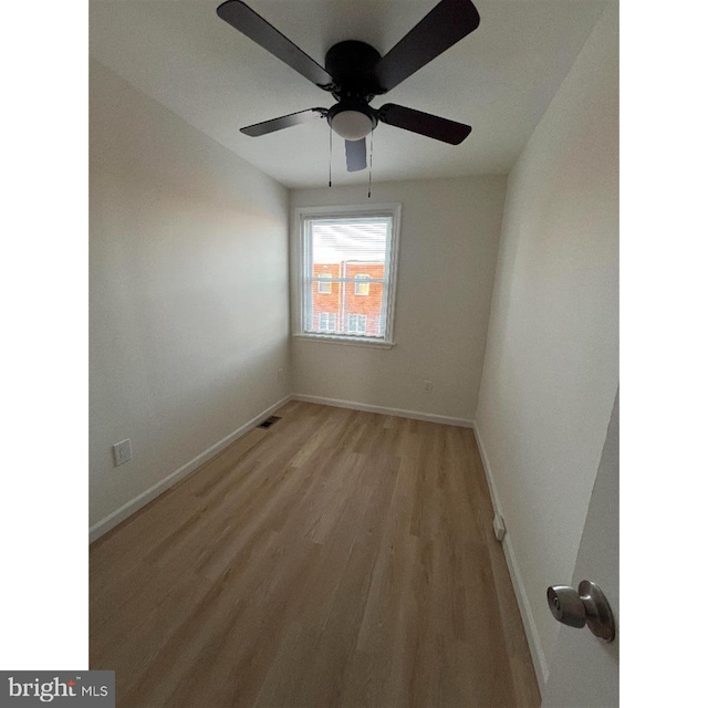 empty room with ceiling fan, light wood-style flooring, baseboards, and visible vents