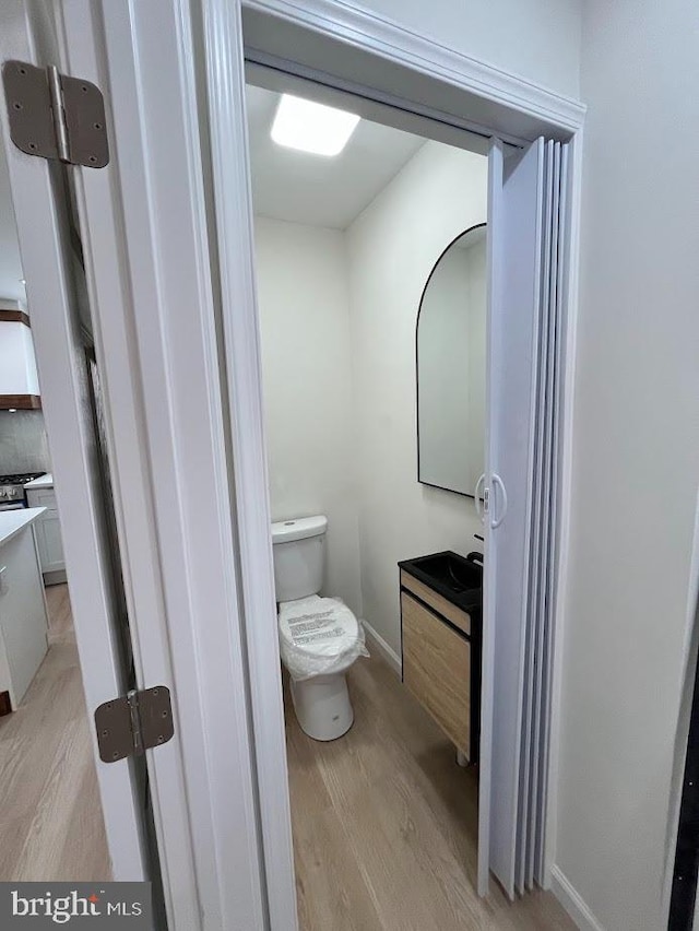 bathroom featuring vanity, toilet, baseboards, and wood finished floors