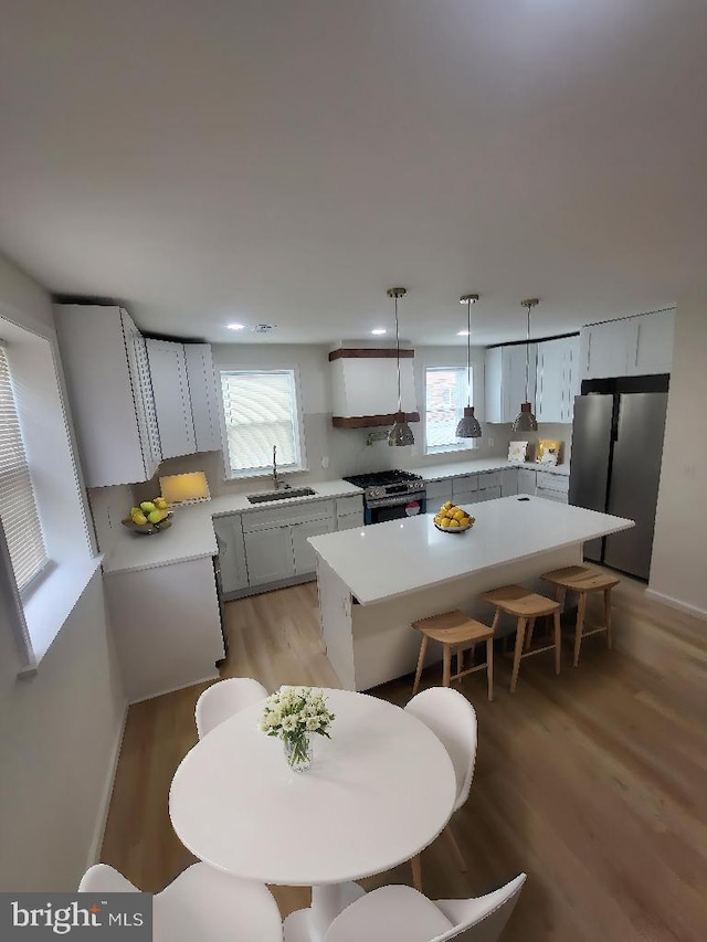 kitchen featuring a sink, stainless steel appliances, light wood-style flooring, a wealth of natural light, and a kitchen island