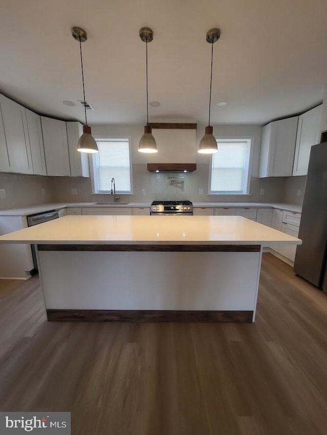 kitchen with wood finished floors, freestanding refrigerator, dishwasher, backsplash, and a center island