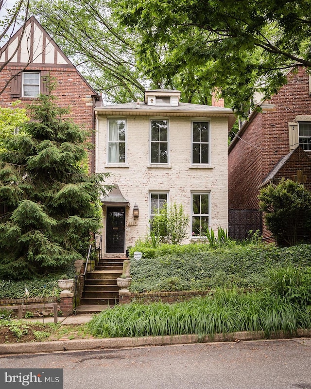 view of front facade featuring a chimney and brick siding