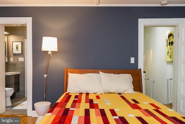 bedroom with radiator, connected bathroom, and wood finished floors