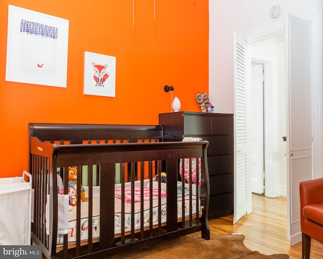 bedroom featuring a nursery area and wood finished floors