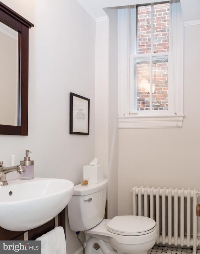 half bath featuring a sink, ornamental molding, toilet, and radiator