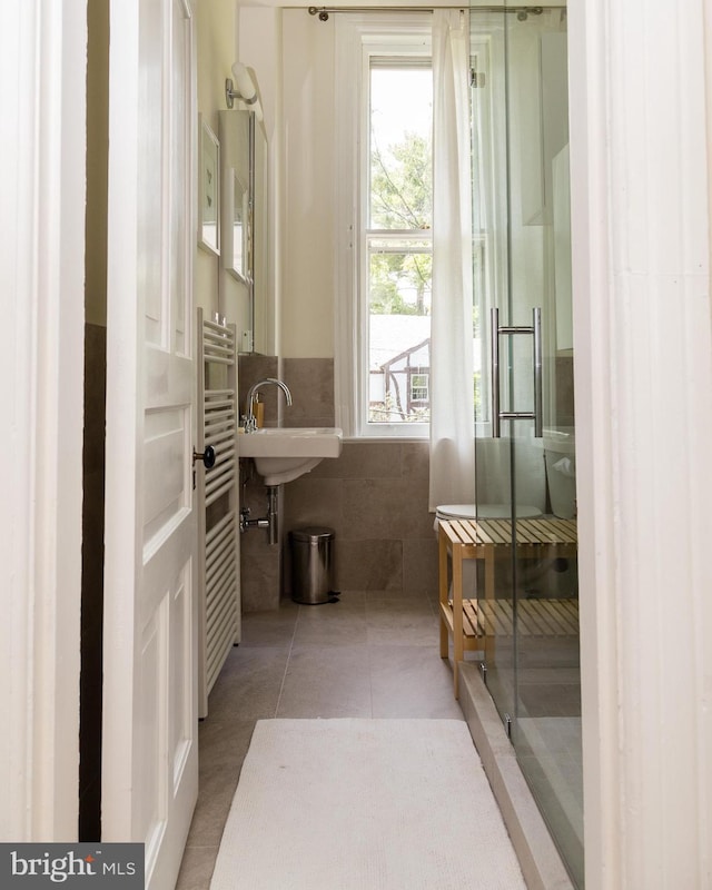 full bath with wainscoting, tile walls, a shower stall, and tile patterned floors