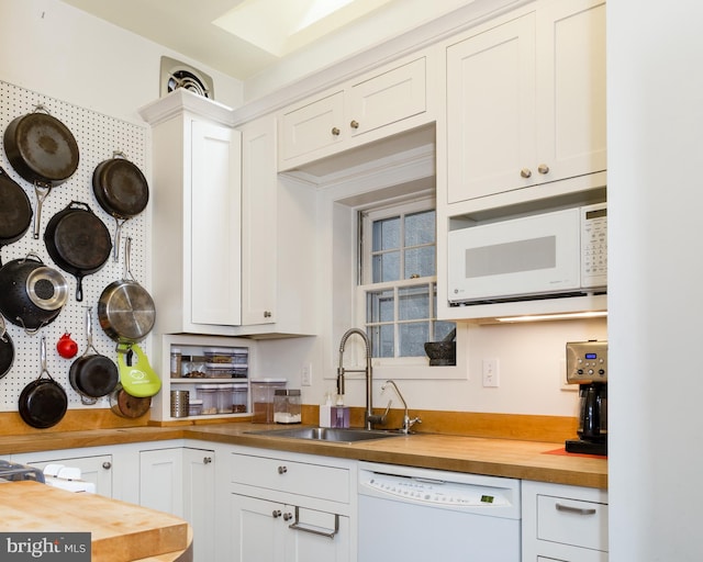kitchen with white appliances, butcher block counters, white cabinets, and a sink