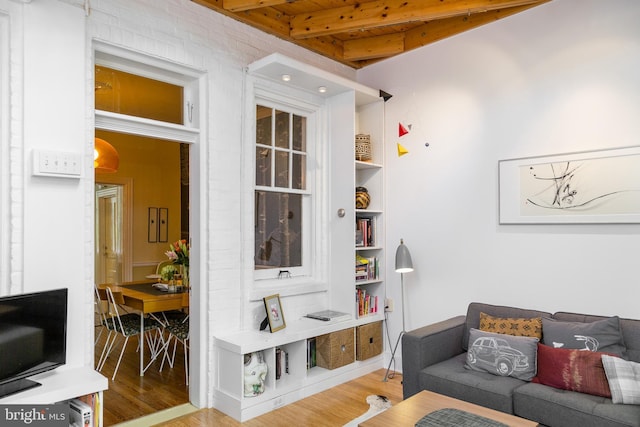 living area with beam ceiling and wood finished floors