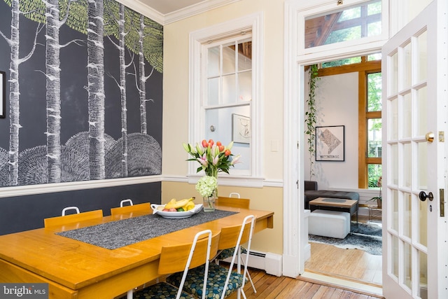 dining area with ornamental molding, a wealth of natural light, hardwood / wood-style floors, and french doors