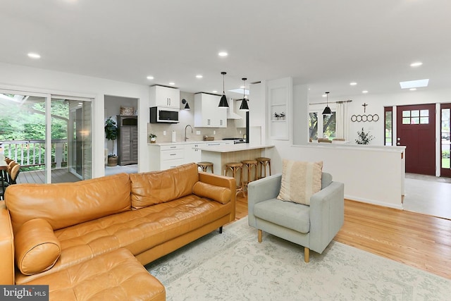 living room with light wood-style flooring, recessed lighting, a skylight, and baseboards