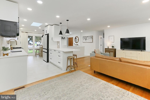 living area with a skylight, recessed lighting, and light wood-style floors