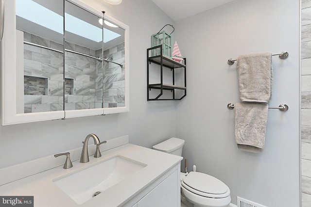 bathroom featuring toilet, vanity, and tiled shower