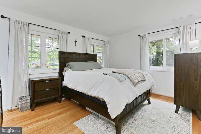 bedroom with multiple windows and light wood-style floors