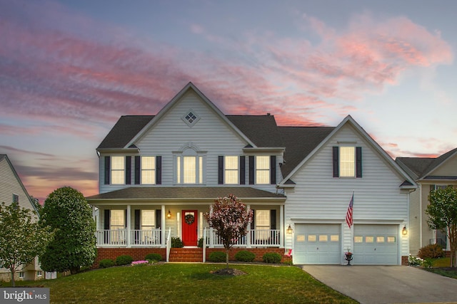 view of front of home with covered porch, a lawn, a garage, and driveway