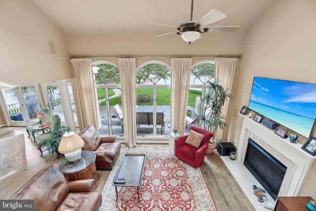 living room featuring wood finished floors, ceiling fan, a fireplace, and lofted ceiling