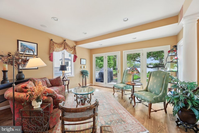 living area featuring wood finished floors, recessed lighting, baseboards, ornate columns, and french doors