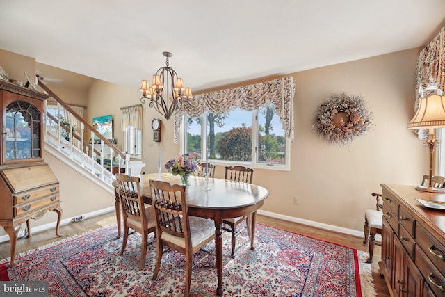 dining space with baseboards, a chandelier, stairs, and wood finished floors