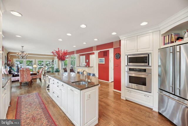 kitchen featuring appliances with stainless steel finishes, a sink, white cabinets, recessed lighting, and dark stone countertops