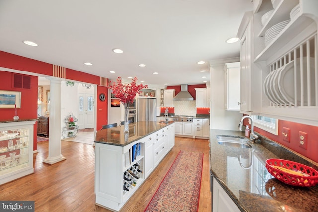 kitchen with a sink, appliances with stainless steel finishes, open shelves, white cabinets, and a center island