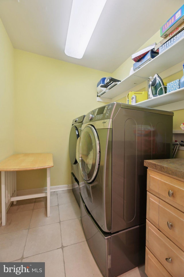 laundry room featuring washer and clothes dryer, baseboards, and light tile patterned floors