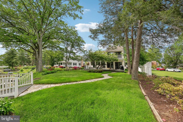 view of green lawn featuring a balcony