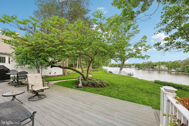 wooden terrace with a water view and a yard