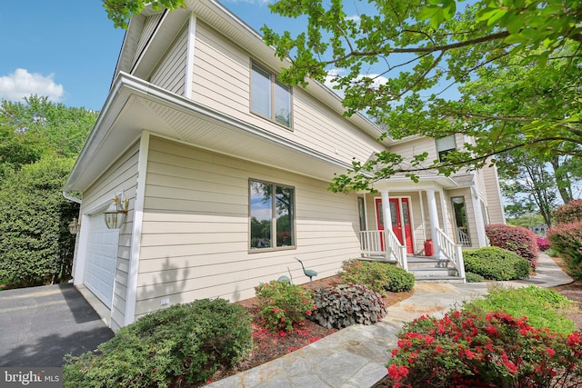 traditional-style home featuring a porch and asphalt driveway