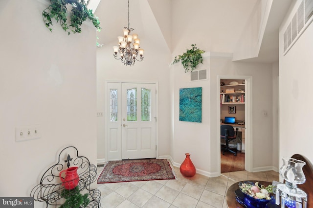 entryway with light tile patterned floors, a chandelier, a towering ceiling, and baseboards