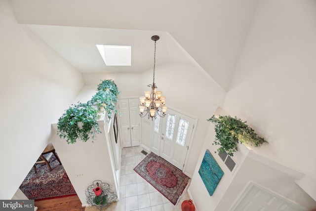 foyer entrance featuring a skylight, a chandelier, and light tile patterned flooring