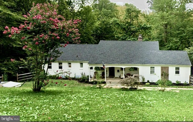 view of front of property with a patio area, a chimney, a front yard, and fence