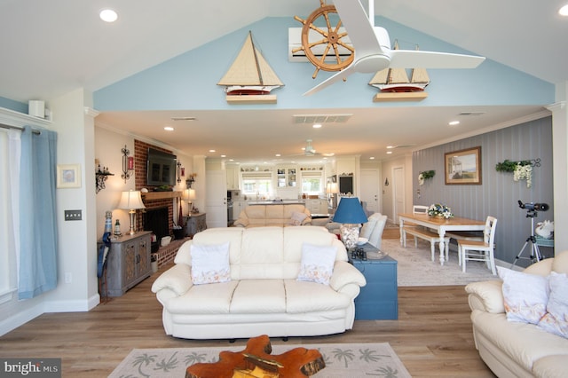 living area featuring crown molding, light wood-style flooring, and a brick fireplace