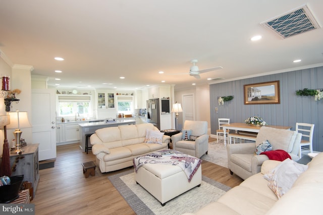 living room with light wood-type flooring, recessed lighting, ornamental molding, and visible vents
