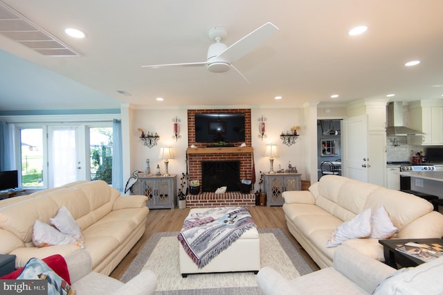 living area featuring light wood-type flooring, visible vents, a ceiling fan, and ornamental molding