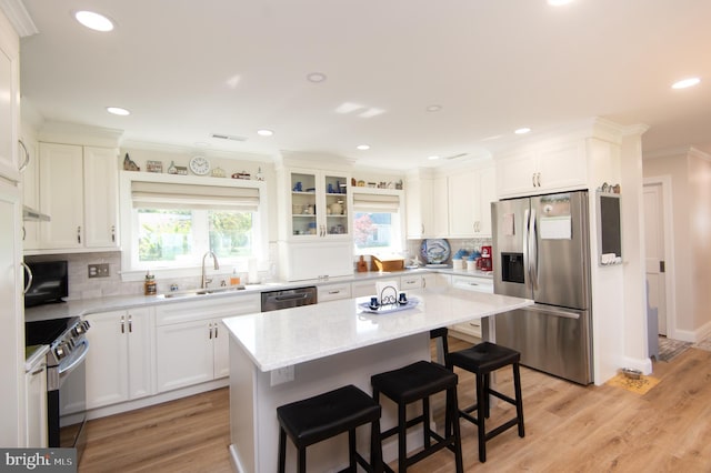 kitchen with a kitchen bar, a sink, stainless steel appliances, crown molding, and backsplash