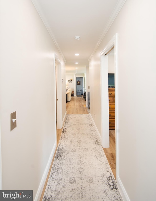 corridor with crown molding, light wood-style flooring, baseboards, and recessed lighting