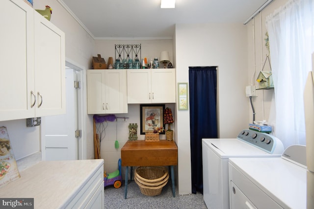 laundry room featuring cabinet space, crown molding, and separate washer and dryer