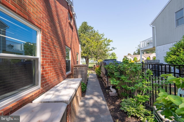 view of side of property featuring brick siding and fence