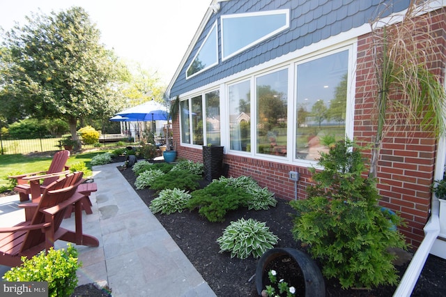 view of side of property featuring brick siding, fence, and a patio area