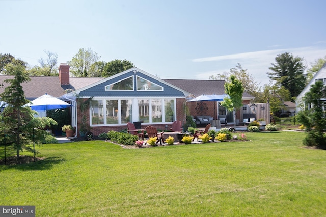 back of house featuring outdoor lounge area, brick siding, a chimney, and a lawn