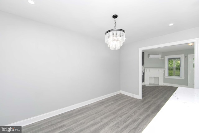 unfurnished dining area with a wall mounted air conditioner, wood finished floors, recessed lighting, an inviting chandelier, and baseboards