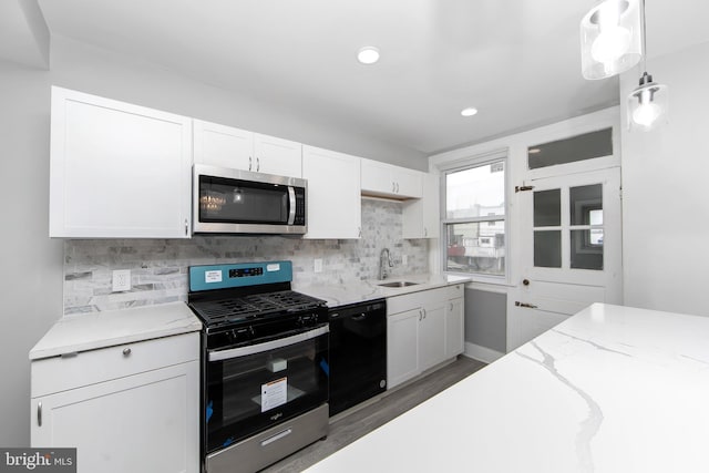 kitchen with a sink, stainless steel appliances, wood finished floors, decorative backsplash, and white cabinets