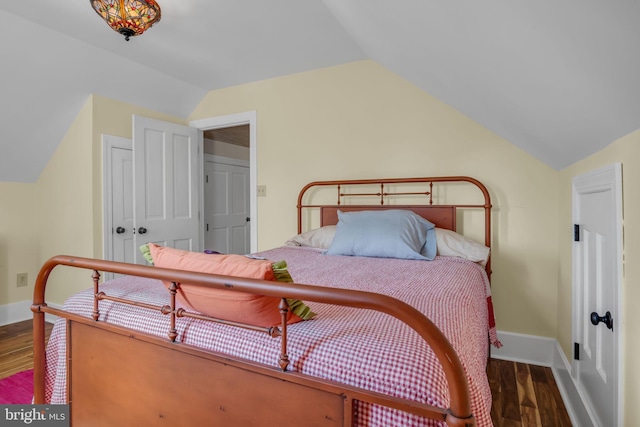 bedroom featuring lofted ceiling, wood finished floors, baseboards, and a closet