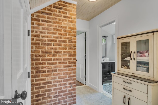 hallway with light carpet, a sink, and wood ceiling