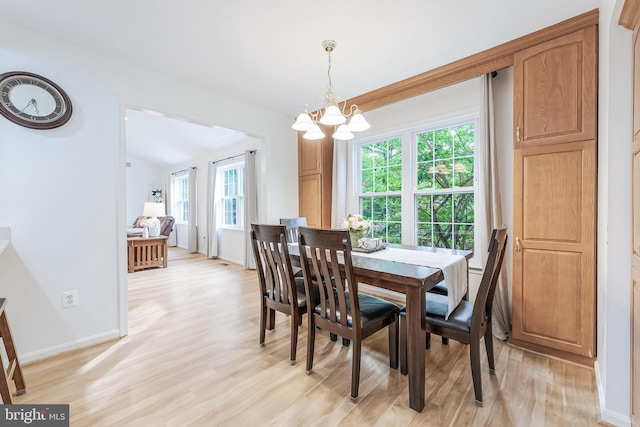 dining room with light wood-style flooring, a notable chandelier, and baseboards